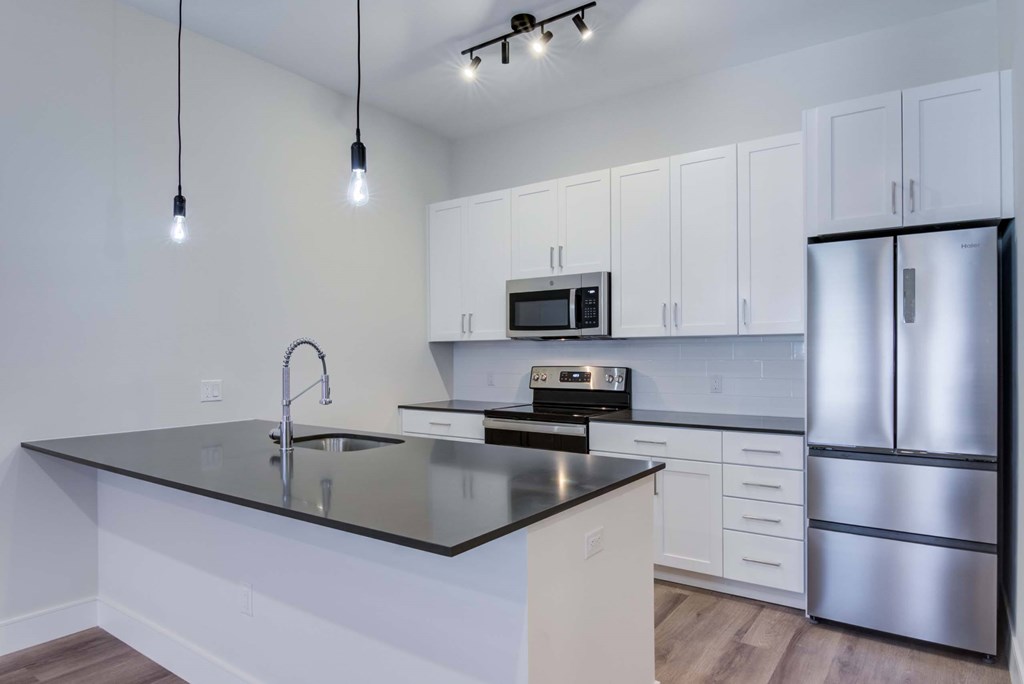 A modern kitchen with a black countertop and stainless steel appliances.