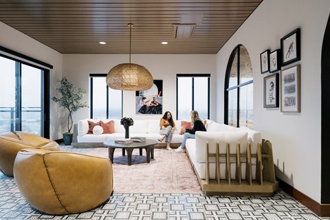 Two women are sitting on a white couch in a spacious living room.