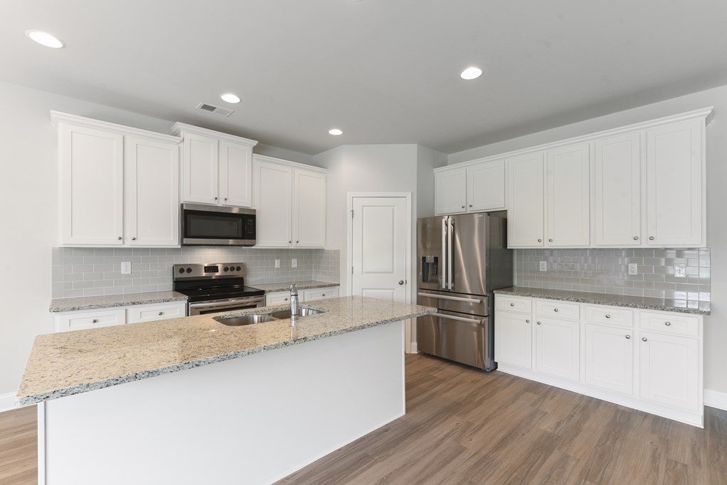 a kitchen with white cabinets and a marble counter top