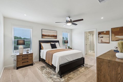A bedroom with a large bed, a ceiling fan, and a rug on the floor.