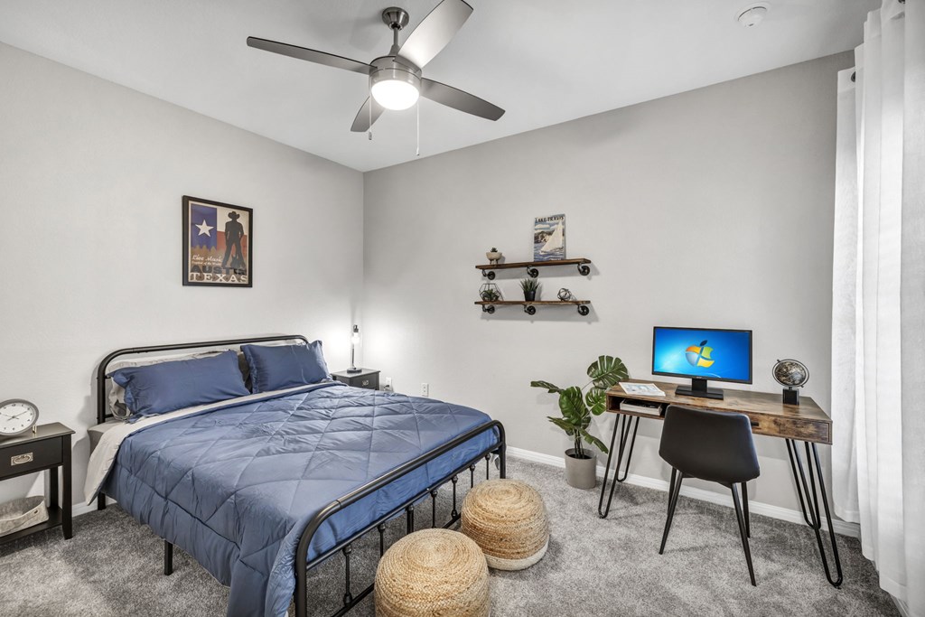a bedroom with a bed and a desk with a computer