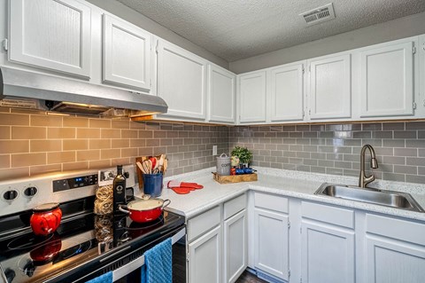 A kitchen with white cabinets and a black stove top.