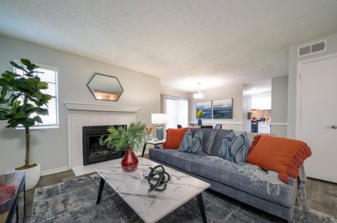 A living room with a grey couch and a fireplace.