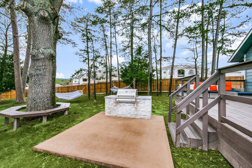 a patio with a grill and a tree