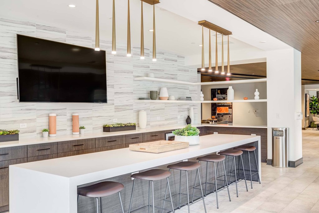 A modern kitchen with a white countertop and stools.