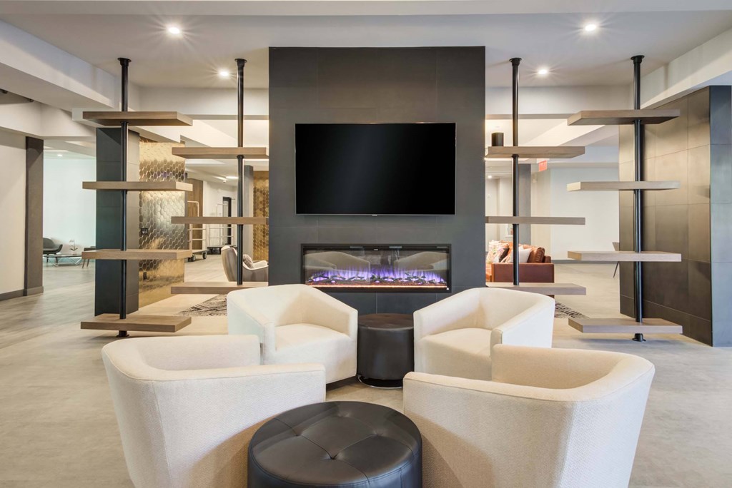 The Beacon clubhouse lounge with chairs, an in-wall fireplace, and wall mounted tv