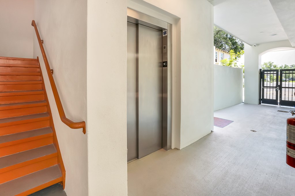 a steel elevator door in a house next to a staircase