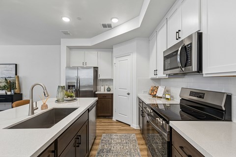 A modern kitchen with white cabinets and stainless steel appliances.