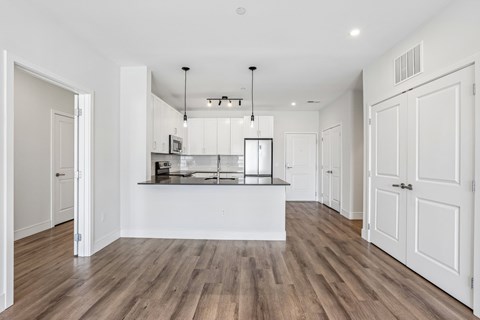 A kitchen with white cabinets and a wooden floor.