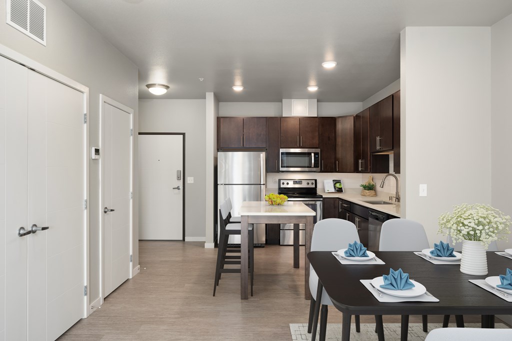 1 BR Apartments in Lakeville MN - Lakeside Flats - Modern Kitchen with Stainless Steel Appliances, Wood-Style Cabinets, White Countertops, Tile Backsplash, Overhead Lighting, Wood Flooring, and Portable Cooking Island Table