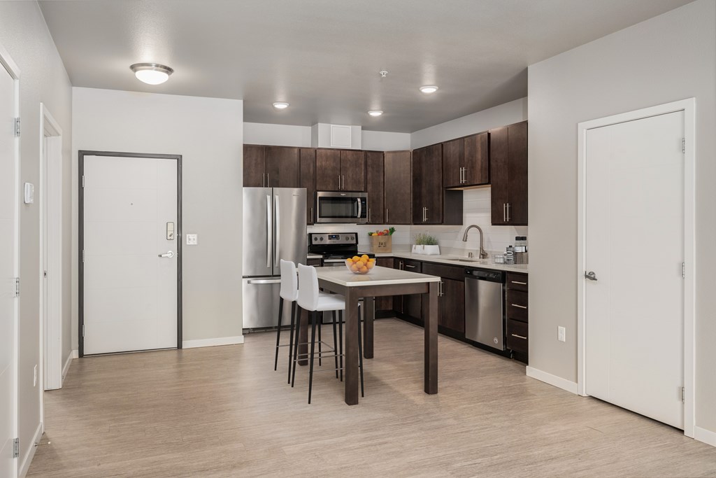 2 BR Apartments in Lakeville MN - Lakeside Flats - Modern Kitchen with Stainless Steel Appliances, Wood-Style Cabinets, White Countertops, Tile Backsplash, Overhead Lighting, Wood Flooring, and Portable Cooking Island Table