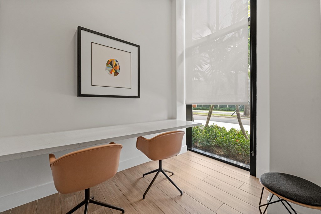 A picture frame hangs on a white wall above a table with two chairs.