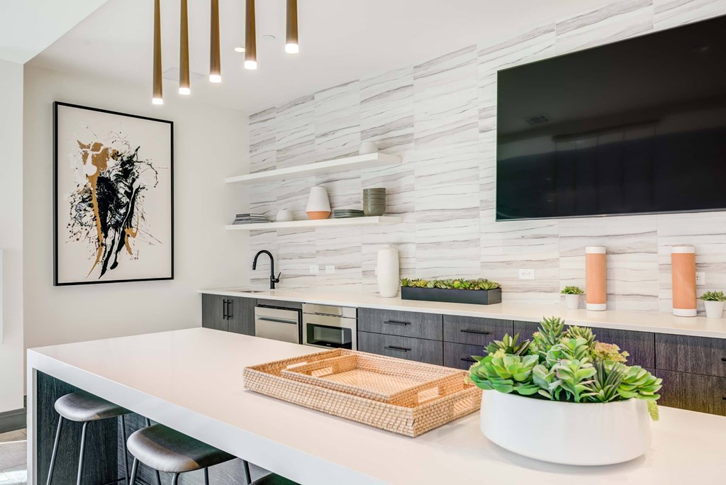 A modern kitchen with a white countertop and a framed picture of a deer on the wall.