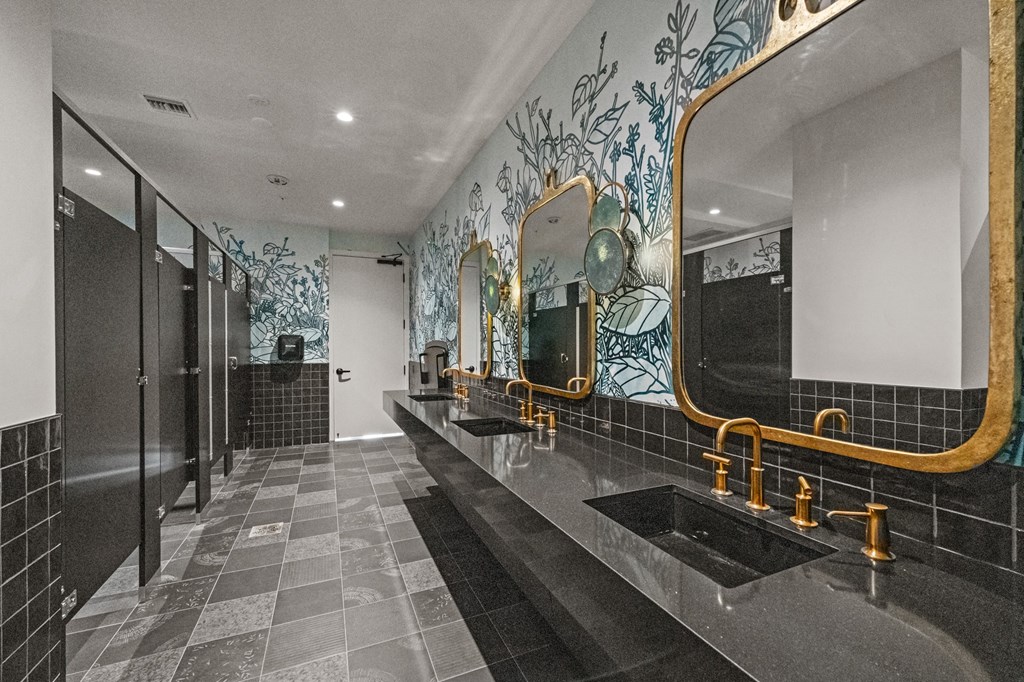 A bathroom with a black and gold sink and mirror.