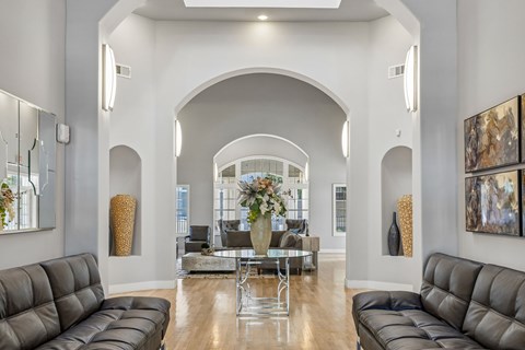 A modern living room with a large grey sofa and a glass coffee table.