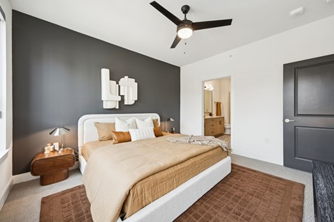 A bedroom with a large bed and a ceiling fan.