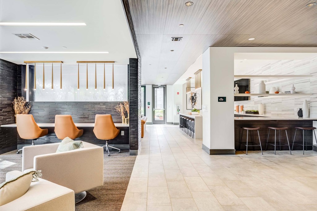 A modern living room with a long white couch and orange chairs.