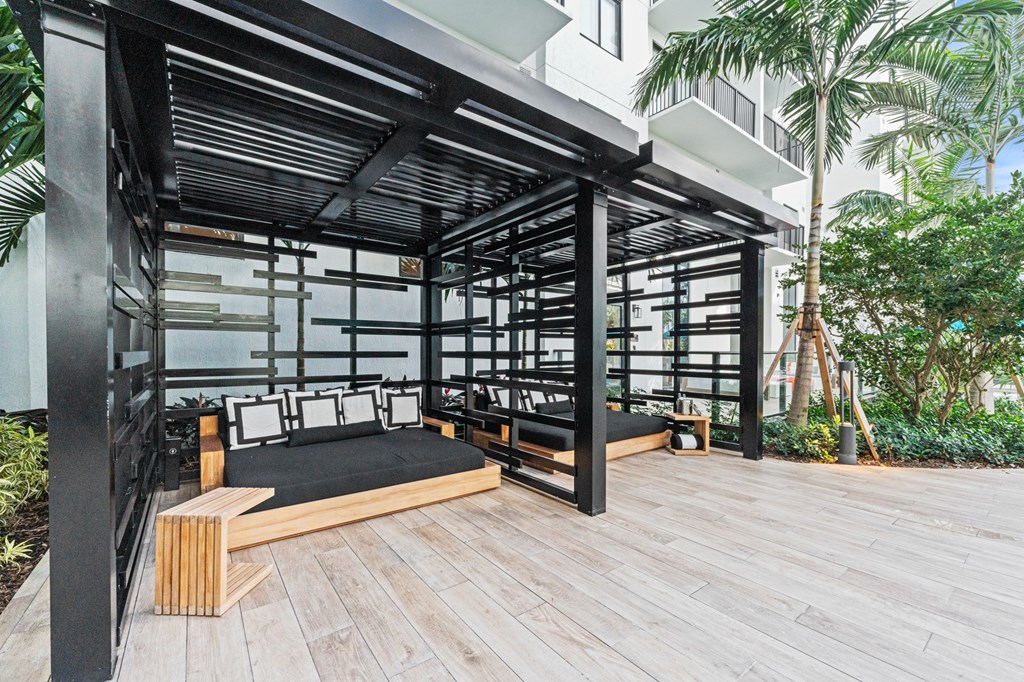 A wooden deck with a black metal pergola and a bed with a wooden headboard.