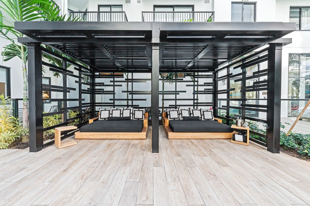 A wooden pergola with black cushions and a black metal frame.