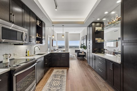 A modern kitchen with dark wood cabinets and stainless steel appliances.