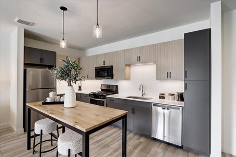 A modern kitchen with a wooden table and bar stools.
