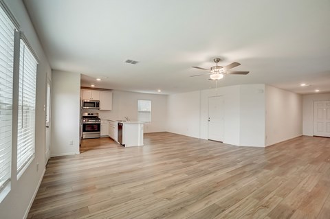 Large living room seamlessly connected to an open concept kitchen, adorned with hardwood floors and flooded with natural lighting