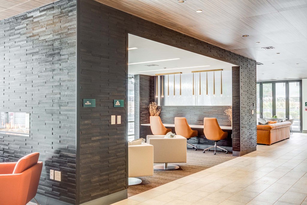 A modern office space with orange chairs and a stone wall.