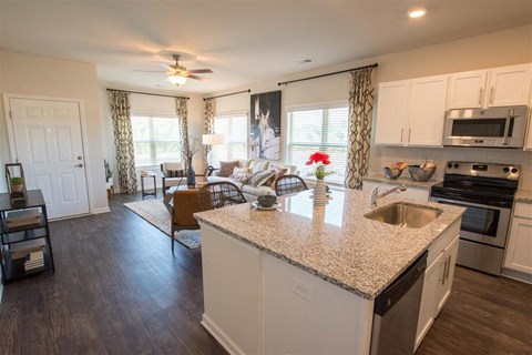 A kitchen with a white island and a dining area with a table and chairs.