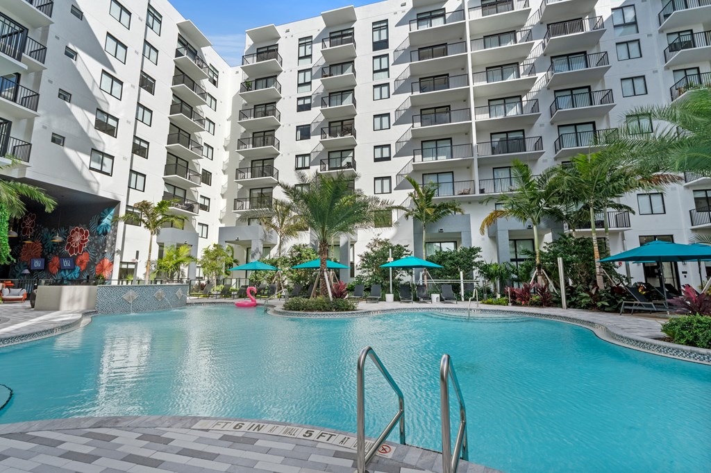 A large swimming pool in front of a white apartment building.