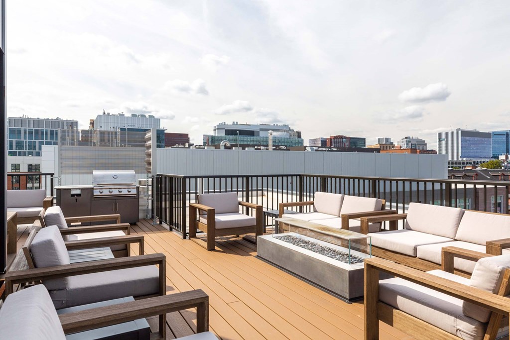 A wooden deck with white cushioned furniture overlooks a city skyline.