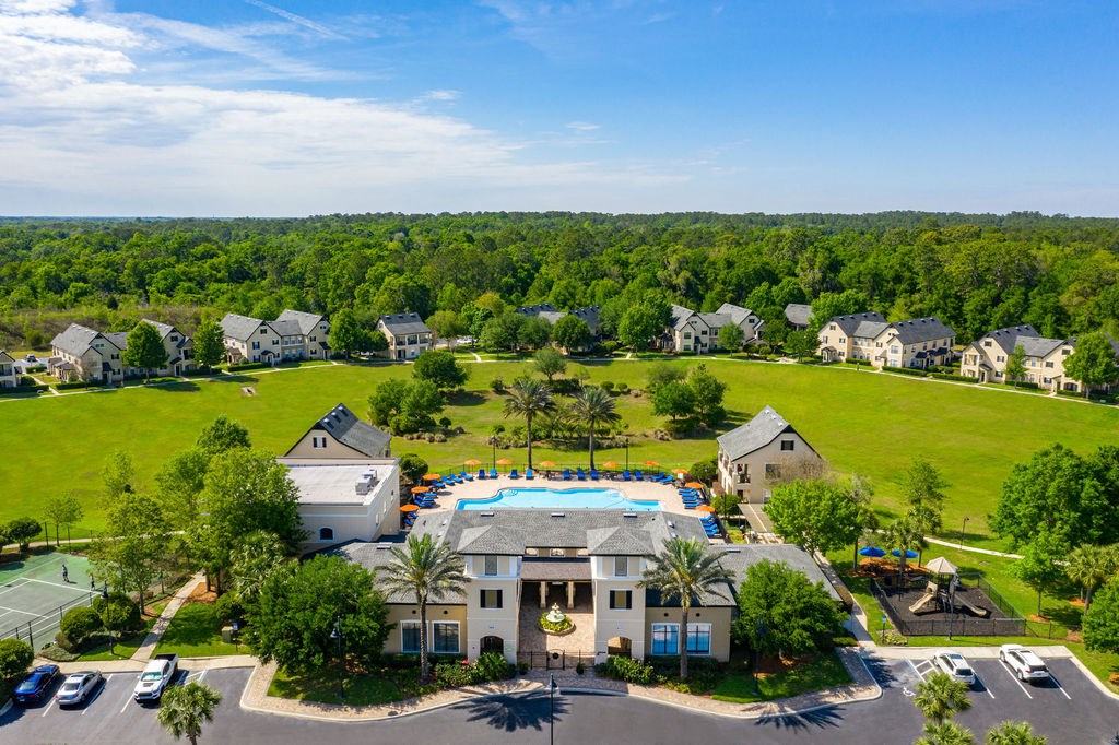 A bird's eye view of a residential area with houses, a swimming pool, and a tennis court.