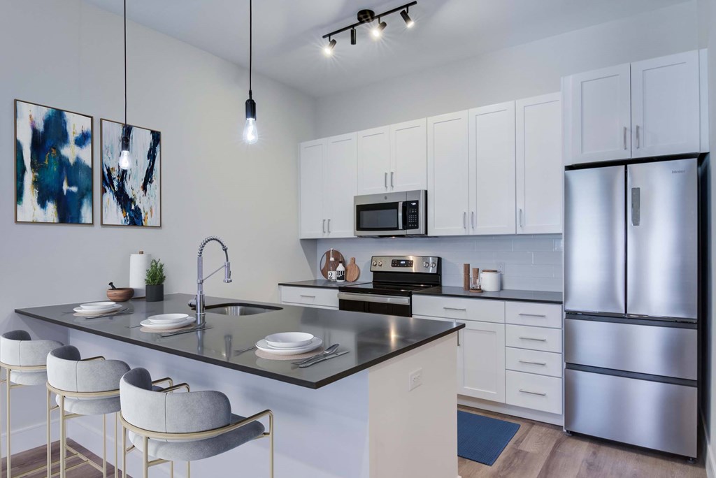 A modern kitchen with a black granite countertop and white cabinets.