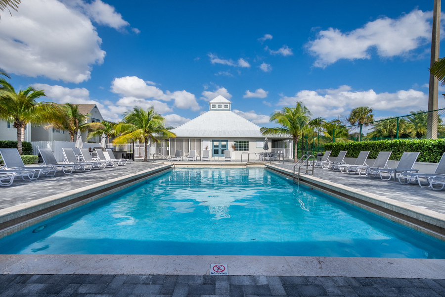 Swimming pool with lounge chairs with exterior view of clubhouse