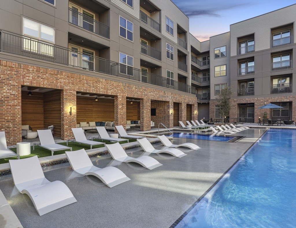 a swimming pool with lounge chairs next to an apartment building