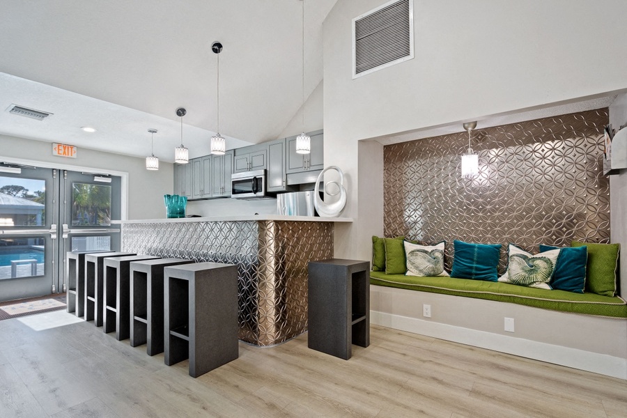 Kitchen area in clubhouse with cabinets, bar seating, pendant lighting and stainless steal microwave