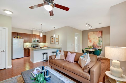 a living room and kitchen with a couch and a ceiling fan