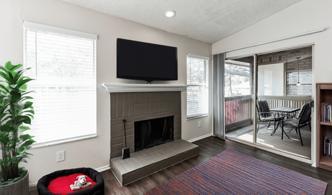 A living room with a fireplace and a television mounted above it.