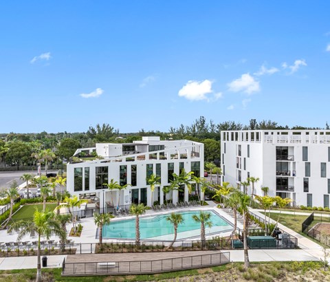 A modern white building with a pool in front.