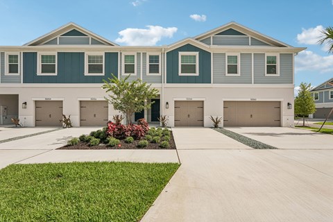 A row of houses with garages and a green lawn in front.