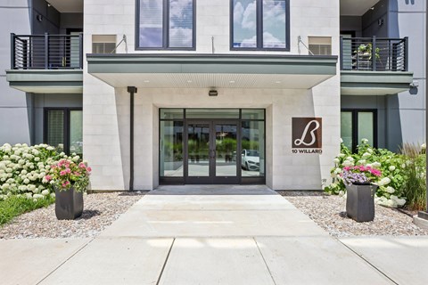 The entrance to a building with a glass door and a brown sign on the wall.