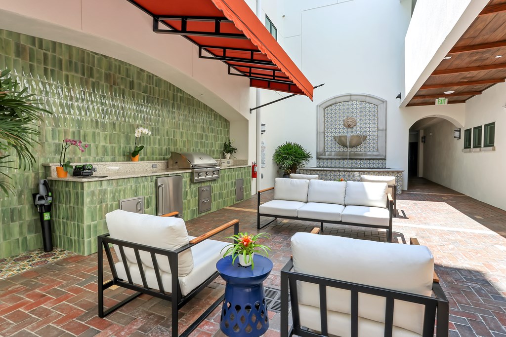 a living room with white couches and a kitchen with green tiles