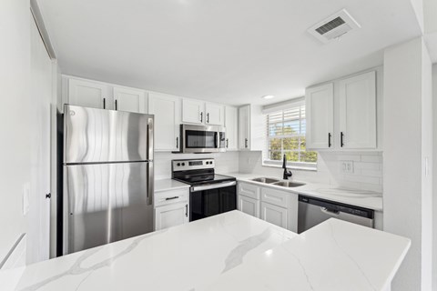 A modern kitchen with a stainless steel refrigerator and black countertops.
