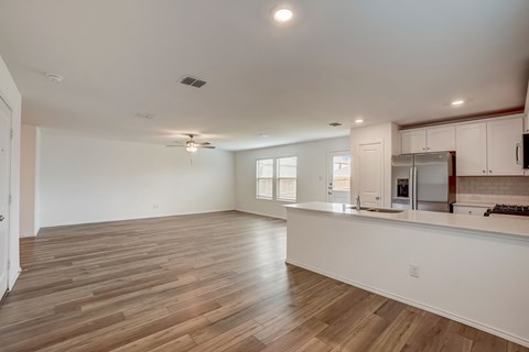 Large living room seamlessly connected to an open concept kitchen, adorned with hardwood floors and flooded with natural lighting