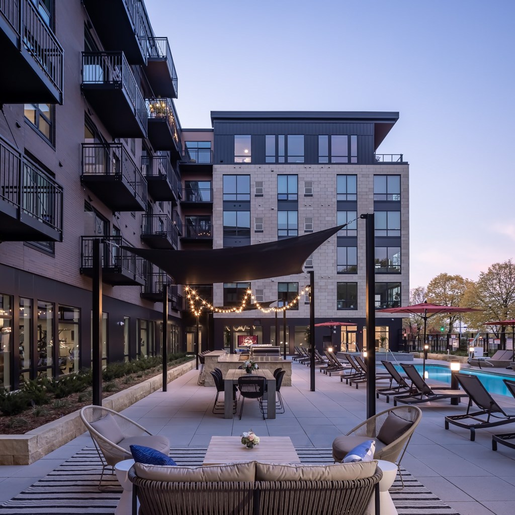 a patio with tables and chairs and a pool at dusk