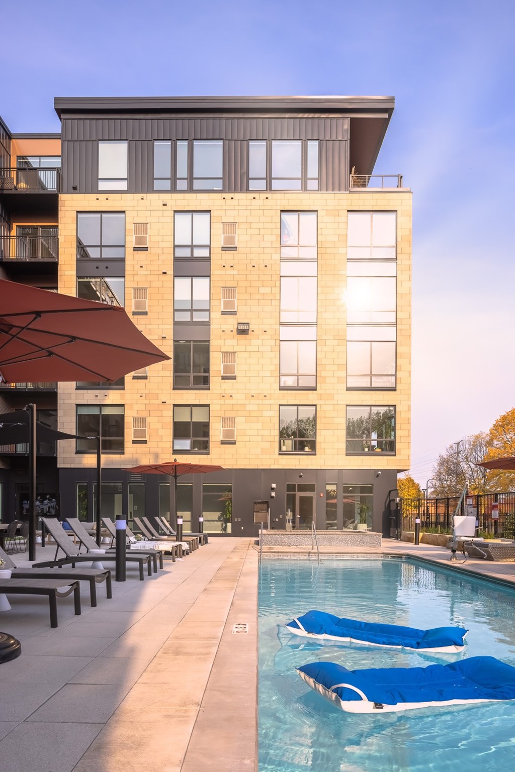 a swimming pool with blue lounge chairs in front of a building