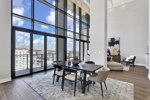 A dining room with a table and chairs in front of a large window.