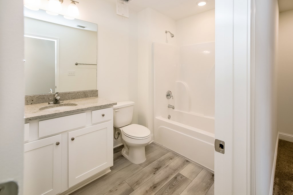 a bathroom with white cabinets and a toilet and a bath tub