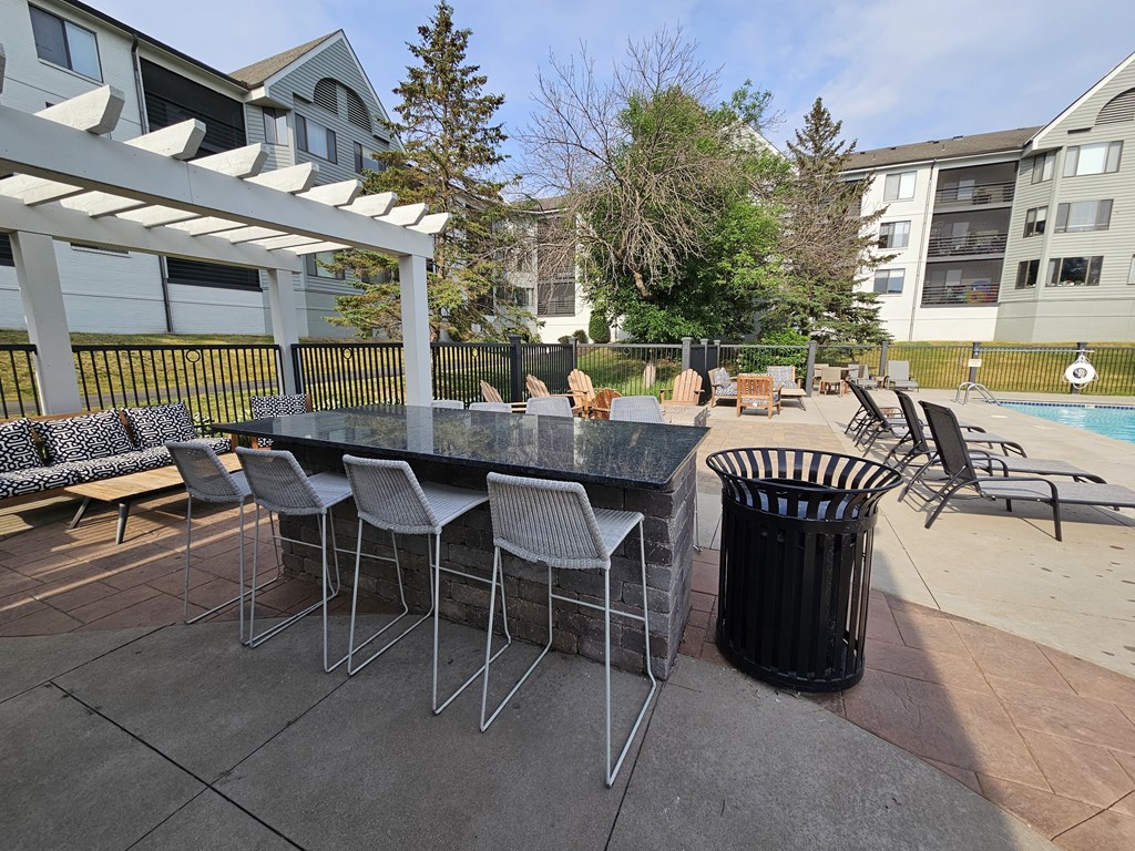 a patio with a table and chairs in front of a pool at The Burlington Apartments in St Paul, MN