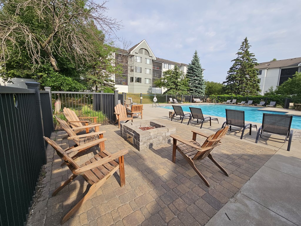 a fire pit and lounge chairs on a patio next to a pool at The Burlington Apartments in St Paul, MN