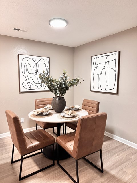 A dining room with a table set for two and two chairs.